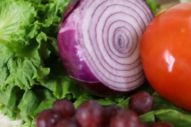 Close-up, assortment of fruit, vegetables: red grapes, lettuce, red onion, tomato at local farmer's market.