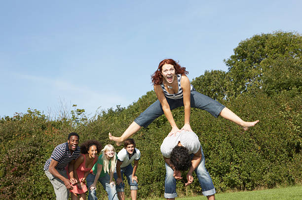 portrait of woman jumping over the top of man - leapfrog - fotografias e filmes do acervo