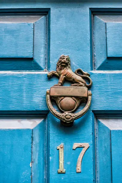 Closeup of blue painted wooden door with the number 17 and lion knocker handle