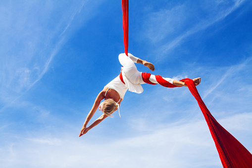 Woman practicing aerial silk yoga outdoors
