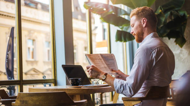 redheaded businessman enjoying the free time for coffee and some news - reading newspaper 30s adult imagens e fotografias de stock