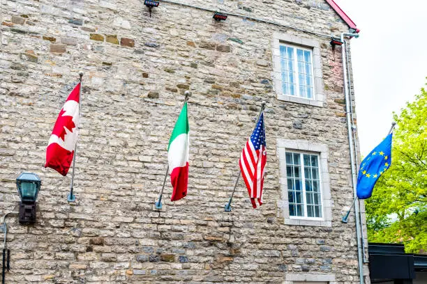 Flags of European and North American countries hanging off building, including Canadian, United States, Italian and European Union