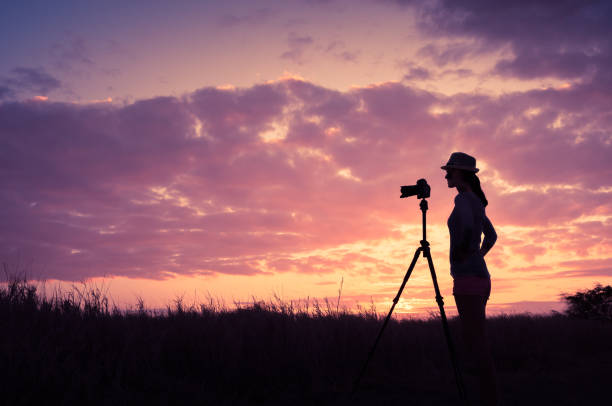 silhouette of a woman with a camera at sunset near the sea beach landscape. High quality photo