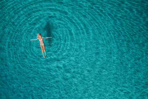 Vista aérea de la mujer de natación en la laguna azul. Mar Mediterráneo en Oludeniz, Turquía. Paisaje de verano con chica, agua azul transparente, olas al amanecer. Agua transparente. Vista superior de volar el drone. Viajes photo