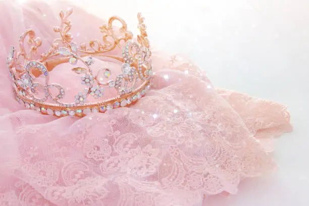 Vintage tulle pink chiffon dress and diamond tiara on wooden white table. Wedding and girl's party concept.