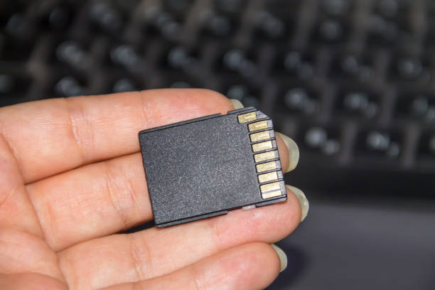 istock Hand holding SD card on laptop background 831502900