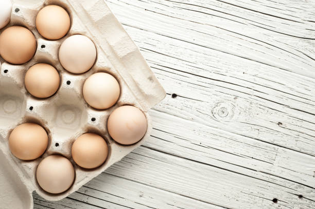 istock chicken eggs in cardboard box on white wooden background 831503318