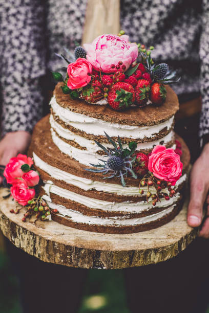 istock groom hold wedding cake with flowers 831506098