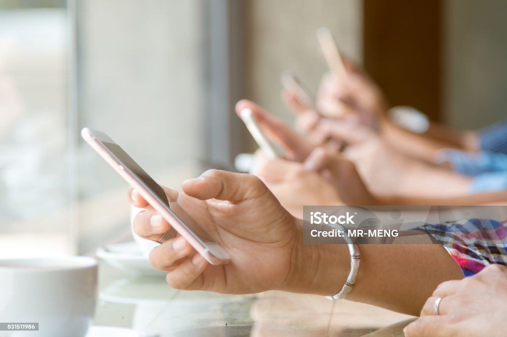 Nahaufnahme von vier Menschen Hand halten Handys und Internet in Coffee-Shop mit warmen hellen Aufflackern - Lizenzfrei Am Telefon Stock-Foto