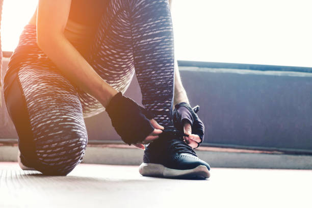 istock Young woman tying her shoelaces before exercise in gym 831518216