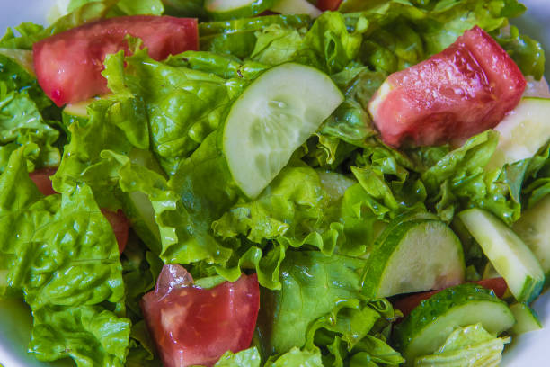 Fresh salad. Tomato, cucumber and greens in white bowl.