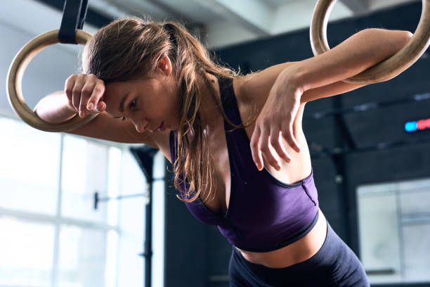 Exhausted Woman Training On Gymnastic Rings Stock Photo - Download