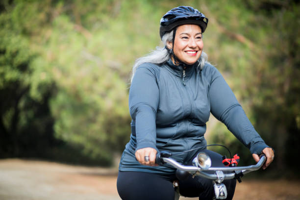 Beautiful Mexican Woman Biking An attractive senior mexican woman biking sports helmet stock pictures, royalty-free photos & images
