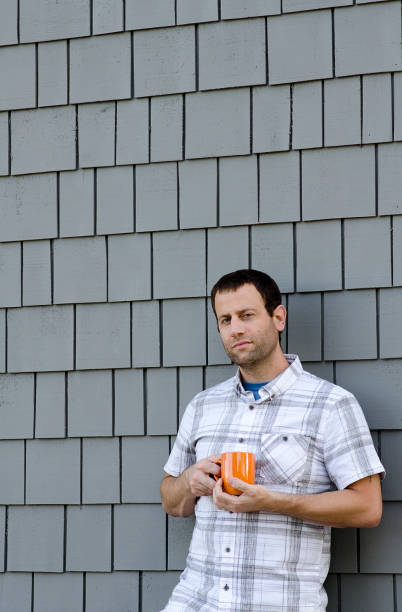 istock Man leaning against a wall holding a coffee mug. 831541194