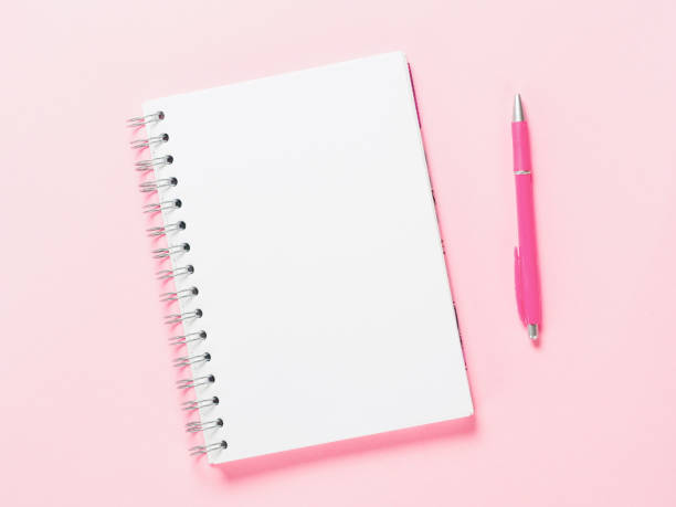 istock Top view of blank note with pen on pink background 831544434
