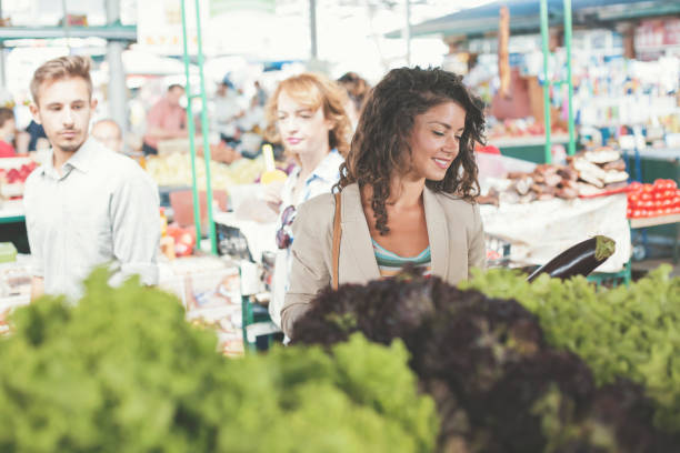 istock Young woman picking up eggplant on market 831550870