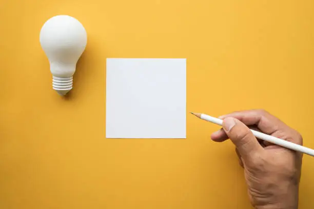 Creativity inspiration,ideas concepts with lightbulb and notepad on pastel color background.Flat lay design.