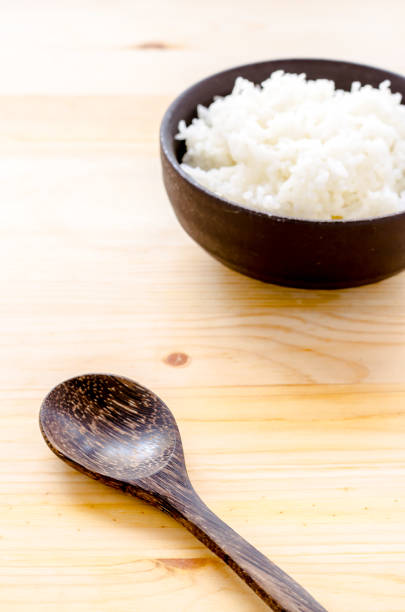 istock Rice in the black bowl on wood table background 831557634