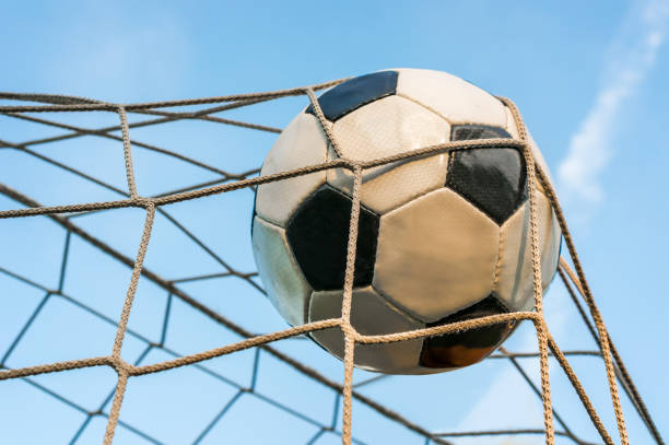 istock Soccer ball in the goal net with blue sky background 831557708