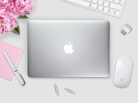 Apple Macbook Pro Retina cover on a desk, table with mouse and stationery. Mockup for cover, decal, sticker design. Trendy office, freelance workplace, top view. White background.