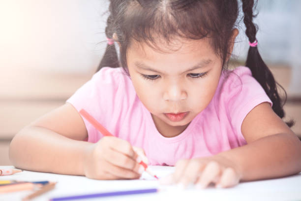 istock Cute asian child girl having fun to draw and paint with crayon 831574444