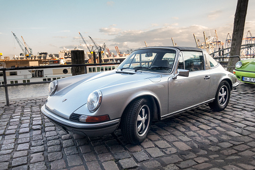 Hamburg, Germany - August 8. 2017: A silvergray Porsche 911, parks on Hamburg Fischmarkt during the event with Magnus Walker. The harbor cranes can be seen in the background.