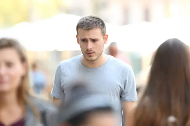 Front view portrait of a sad boy walking on the street