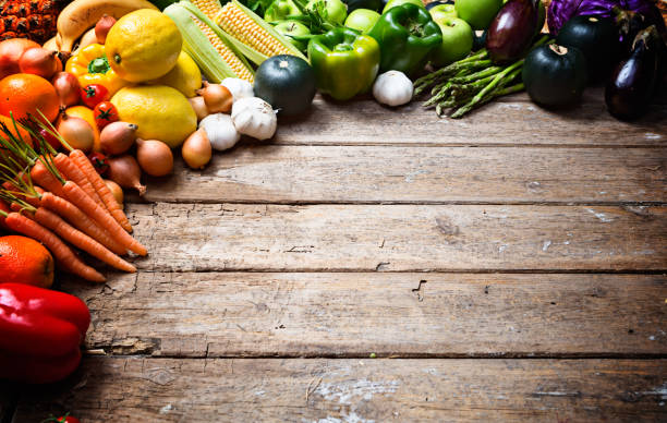 istock Multicoloured fruit and vegetables form frame on weathered wood 831591316