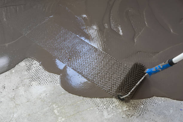 istock Interior of apartment under construction. Spreading self leveling plaster with a special roller 831597192