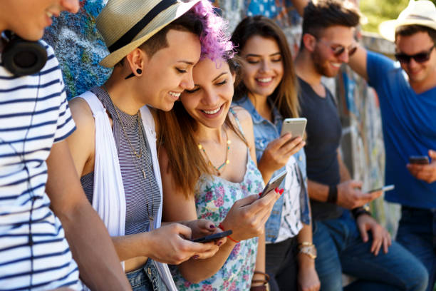 istock Multi-ethnic group of teenagers using smart phones while leaning against wall 831600730