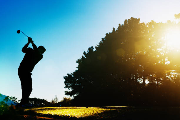 silhouette golfer abschlag bei sonnenaufgang - golf golf course sunrise morning stock-fotos und bilder