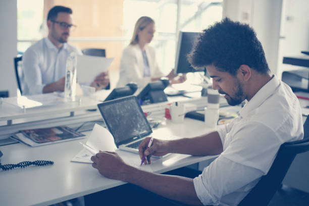 istock Business people working in office. African man writing on document. 831618588