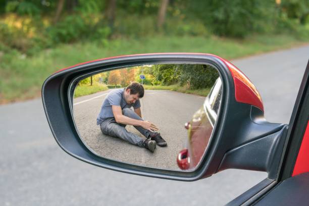Hit and run concept. View on injured man on road in rear mirror of a car. stock photo