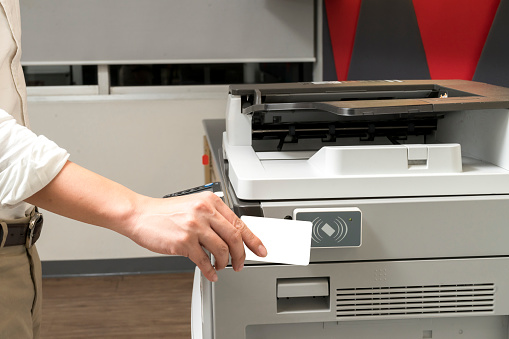 man hand hold card for scanning key card to access Photocopier . Security system concept