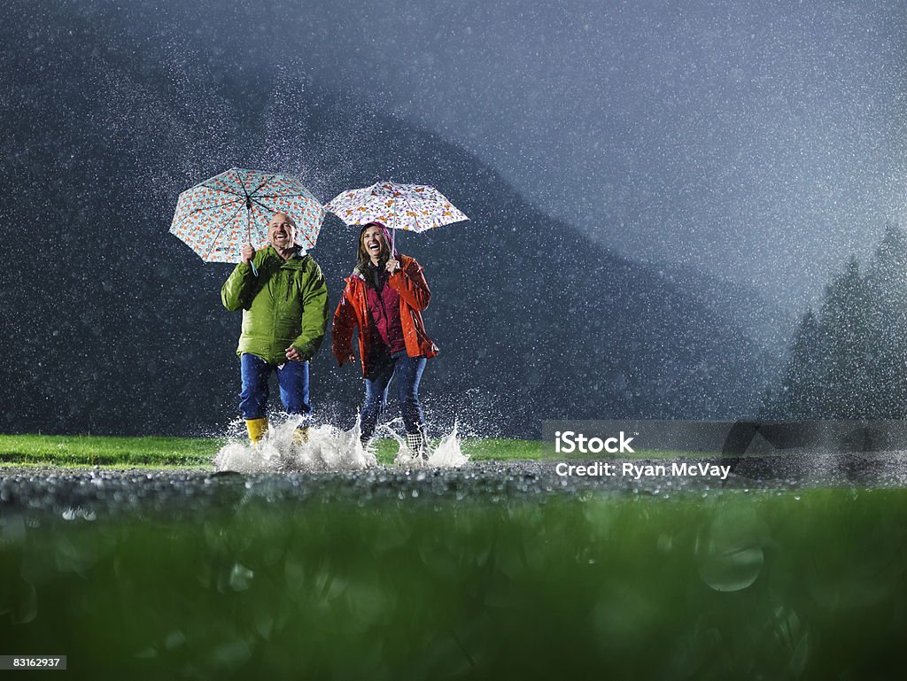 Mann und Frau mit Sonnenschirmen Spielen im Regen. - Lizenzfrei Regen Stock-Foto