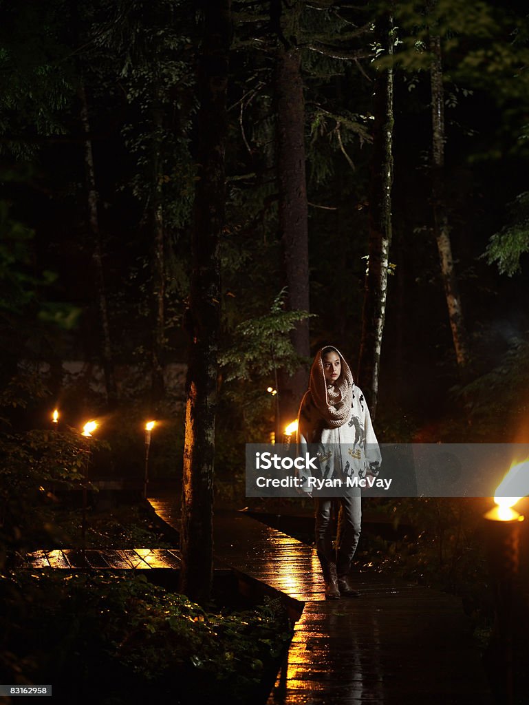 Woman walking along rainy pathway at night.  Walking Stock Photo