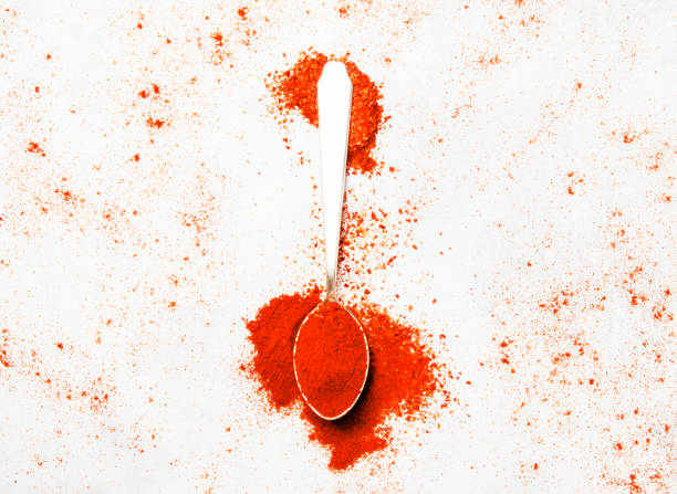 istock Ground chili pepper in a silver spoon, spice background, top view 831635428