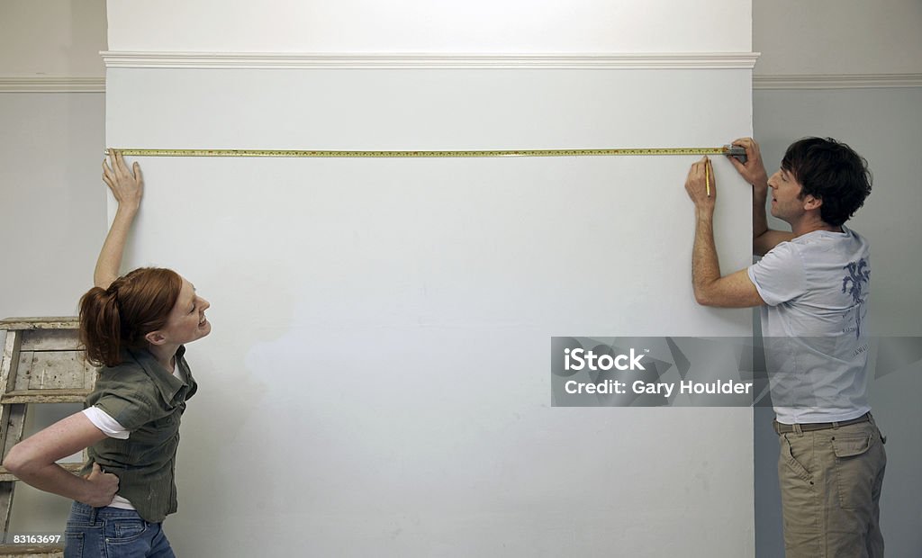 Casal de medição e marcação de uma parede - Foto de stock de Medindo royalty-free