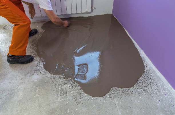 istock Worker puts a self leveling screed with trowel on concrete floor in house 831637810