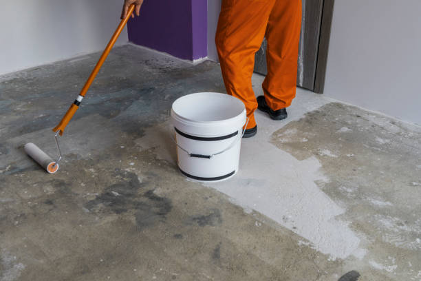 istock Worker puts primer with roller on concrete floor in house 831638712