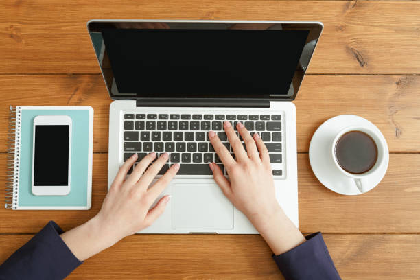 istock Female using laptop in coffee shop, close-up, top view 831640204