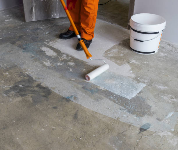 istock Worker puts primer with roller on concrete floor in room from unfinished apartment 831644218