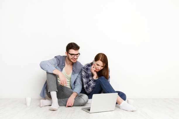 istock Couple at food delivery web site on laptop, calling on mobile to make an order 831653458