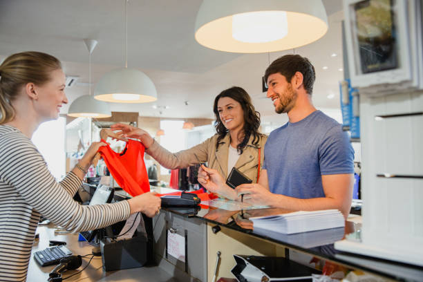 Couple Purchasing Clothing A couple shopping in an exclusive fashion clothing store, using their credit card to buy new clothes clothing store credit card stock pictures, royalty-free photos & images