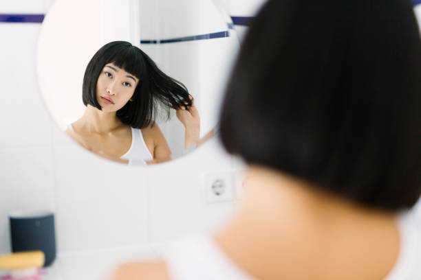 istock Asian Woman looking at her mirror image in the bathroom 831657178