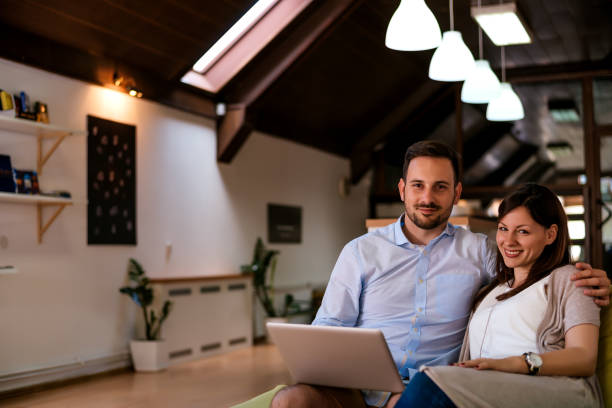 istock Happy young married couple sitting on the sofa hugging 831664716