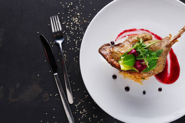 istock Restaurant meals. Duck confit with vegetables on black background 831679602