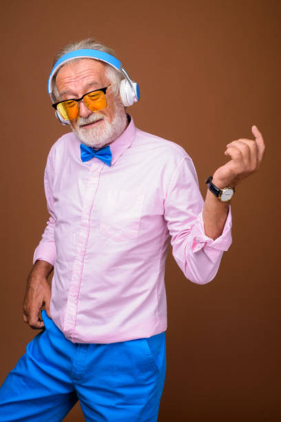 Studio shot of senior handsome man wearing stylish clothes against colored background Studio shot of senior handsome man wearing stylish clothes against colored background vertical shot air guitar stock pictures, royalty-free photos & images