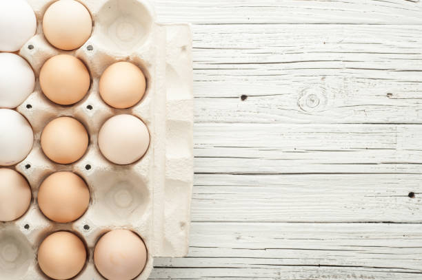 istock chicken eggs in cardboard box on white wooden background 831700554