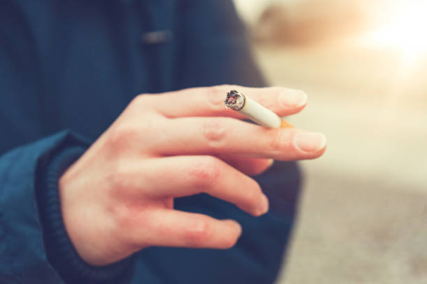 donna che fuma una sigaretta filtrante all'aperto - smoking women smoke smoking issues foto e immagini stock